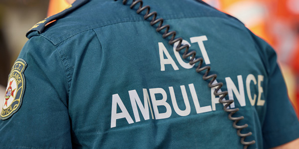The back of a paramedic with ACT AMBULANCE written on the shirt