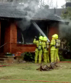 Firefighters dampen down after extinguishing a house fire in Waramanaga. Pic by Murray Charlton.